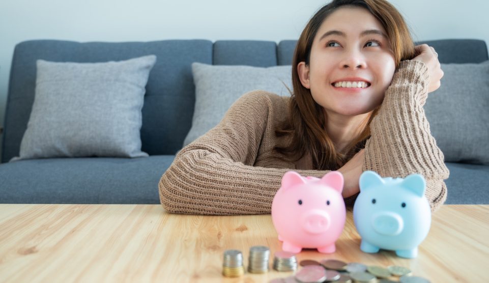 Egy lány mosolyog két persely felett