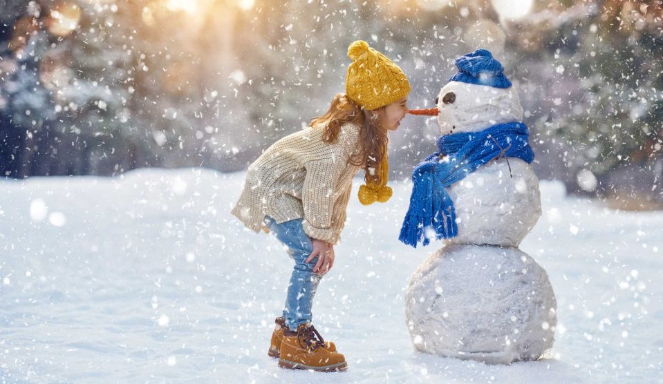 kislány a hóesésben egy hóemberrel