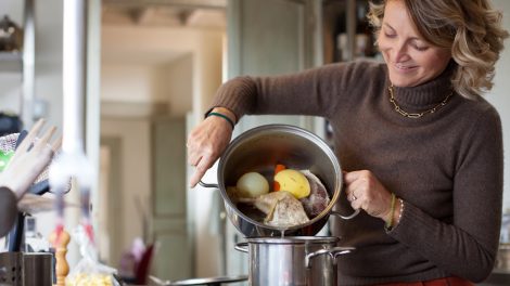 középkorú háziasszony leönti a húsleves első főzővizét