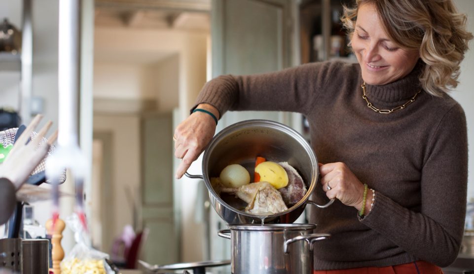 középkorú háziasszony leönti a húsleves első főzővizét