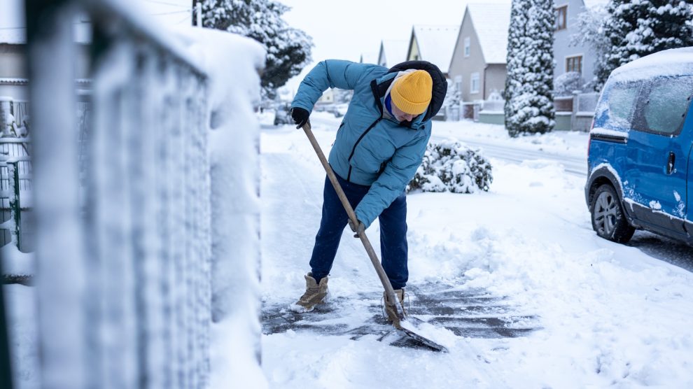 Egy férfi havat lapátol