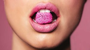 nő rúzsozott szájában cukor
