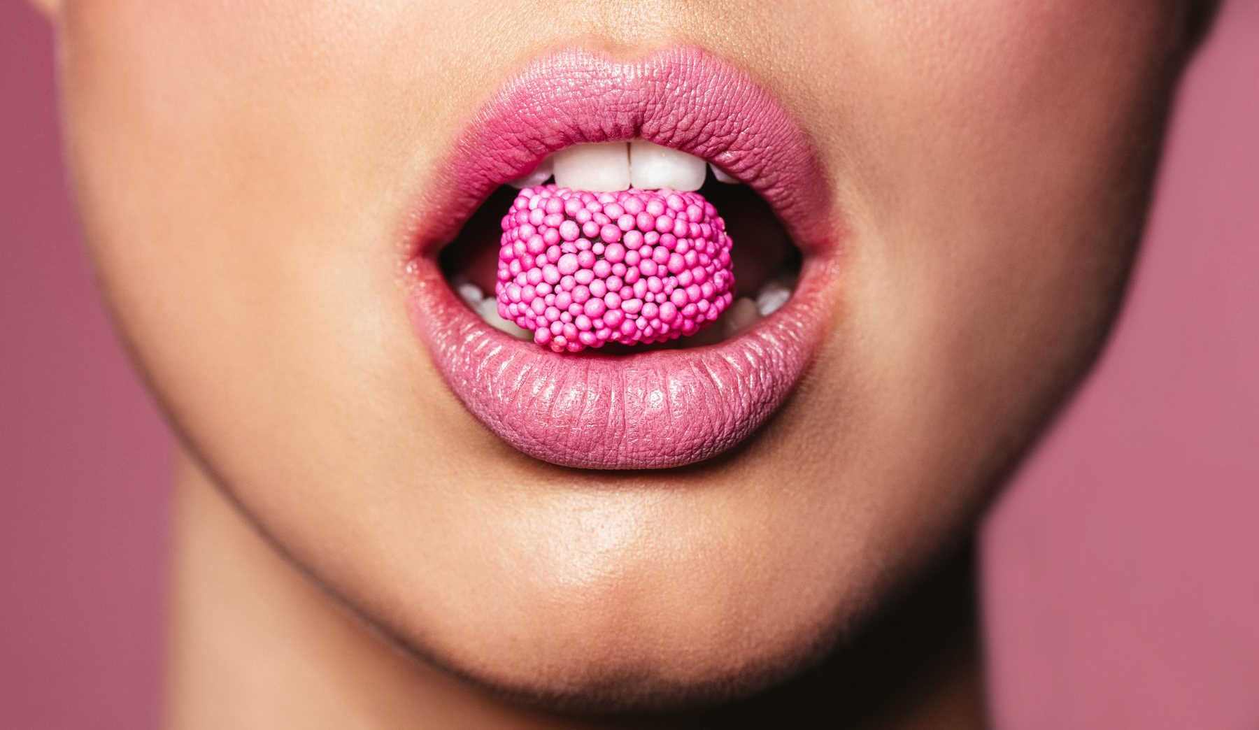 nő rúzsozott szájában cukor