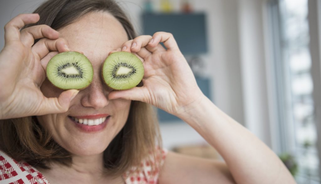 mosolygós vidám nő kivit tart a szeméhez viccből