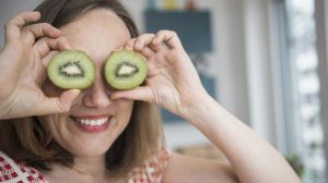 mosolygós vidám nő kivit tart a szeméhez viccből