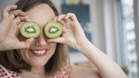 mosolygós vidám nő kivit tart a szeméhez viccből