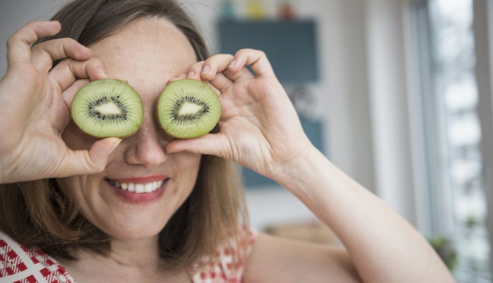 mosolygós vidám nő kivit tart a szeméhez viccből