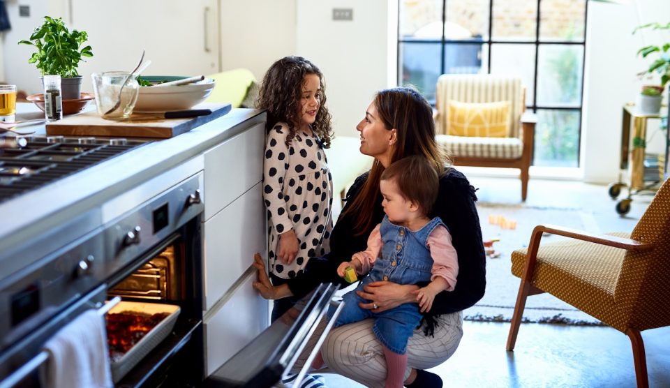 Egy család áll a konyhában a sütő mellett