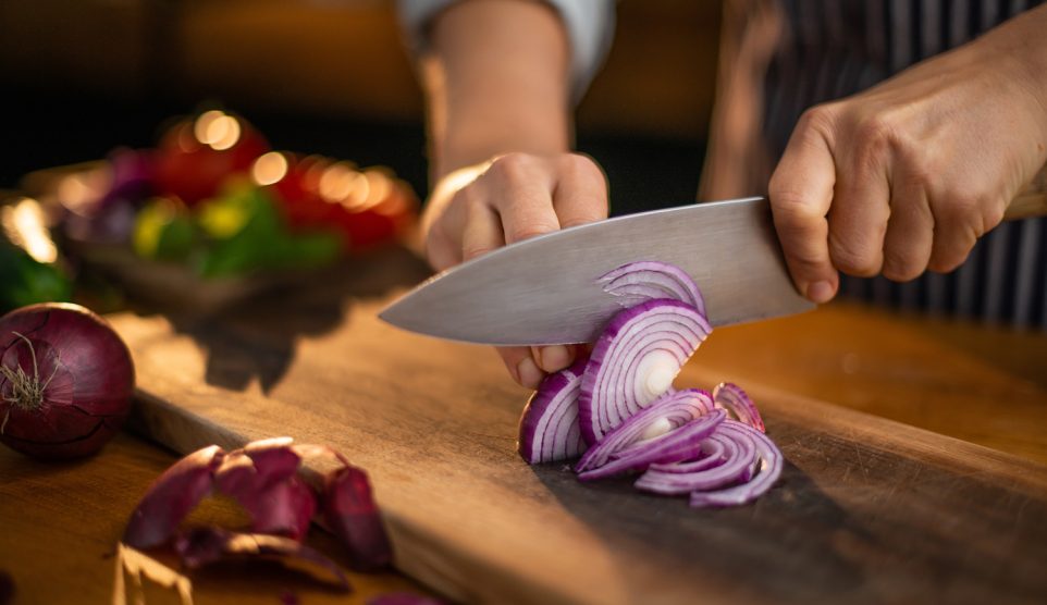 lilahagymát vág vágódeszkán egy férfi