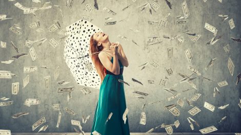 szerencsés boldog nő áll a pénzesőben