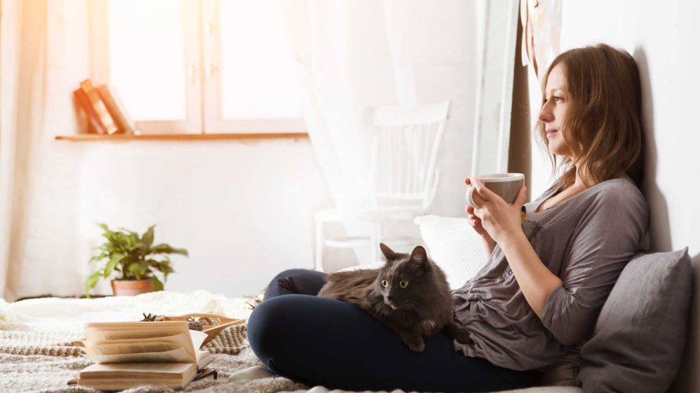 nő heverészik a macskájával az ágyban