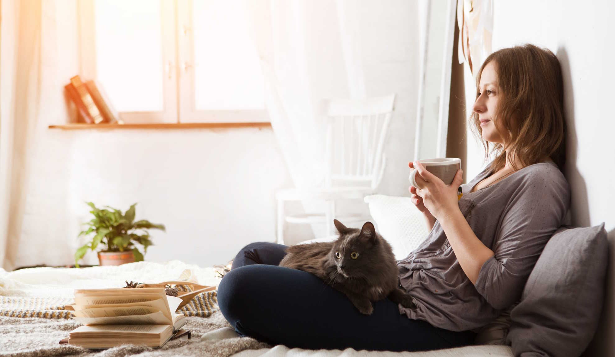 nő heverészik a macskájával az ágyban