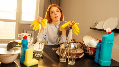 Boldogtalan nő sárga kesztyűvel, piszkos edények mellett