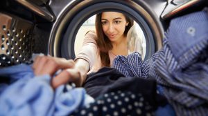 Mosógépből pakol ki egy nő