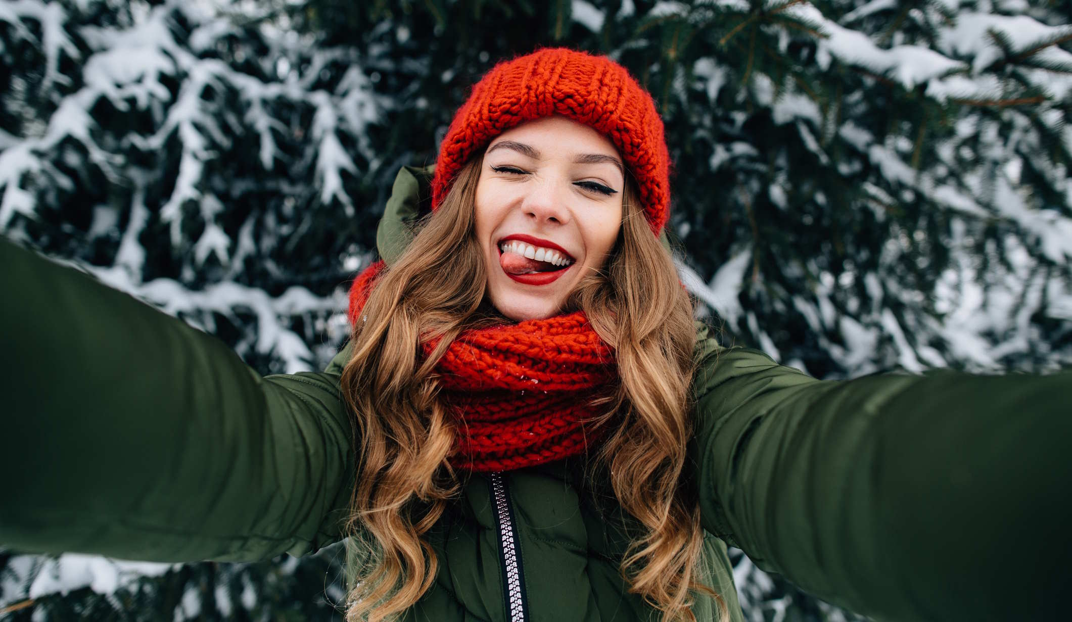 fiatal lány piros sapkában szelfizik a havas háttérrel