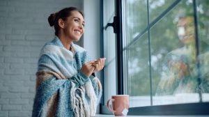 nő áll az ablakban a jó meleg szobában