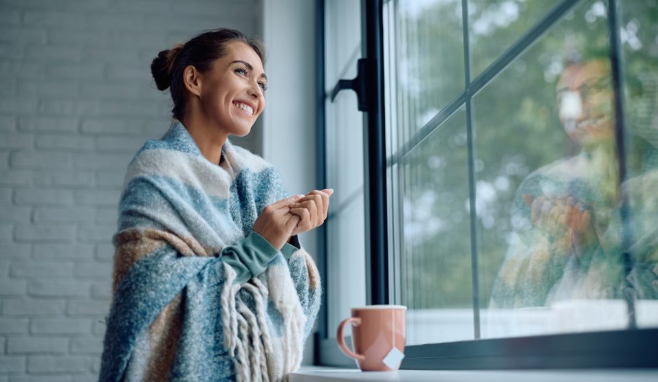 nő áll az ablakban a jó meleg szobában