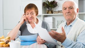 nyugdíjat számol egy idős házaspár a konyhaasztalnál