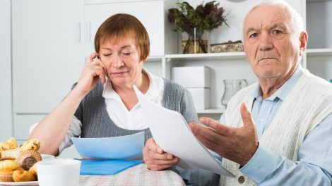 nyugdíjat számol egy idős házaspár a konyhaasztalnál
