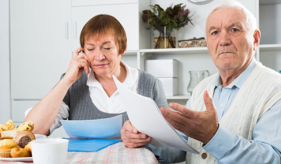 nyugdíjat számol egy idős házaspár a konyhaasztalnál