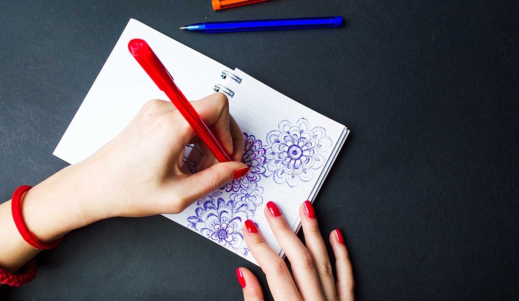 nő rajzolgat a jegyzetfüzetébe