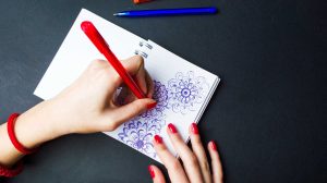 nő rajzolgat a jegyzetfüzetébe