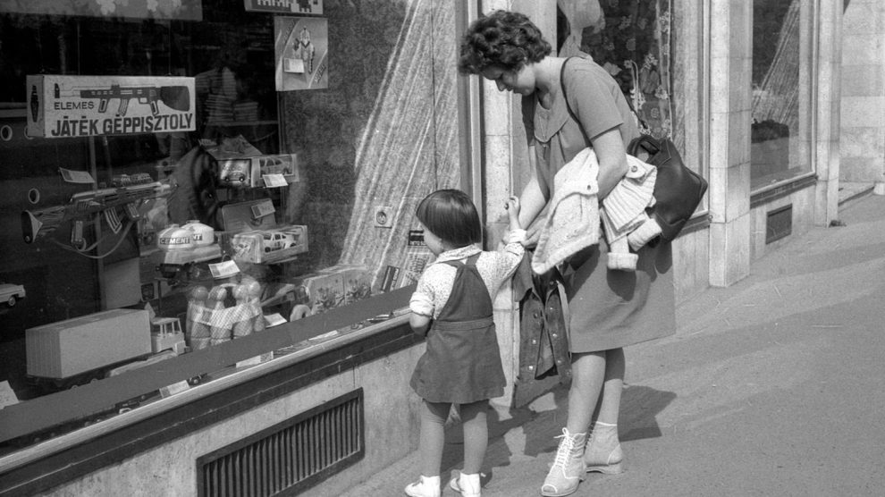 gyerekjátékokat nézeget a kirakatban egy anyuka és kislánya az 1980-as években retró fotó