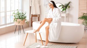 Fiatal nő testápolót ken magára a fürdőszobában