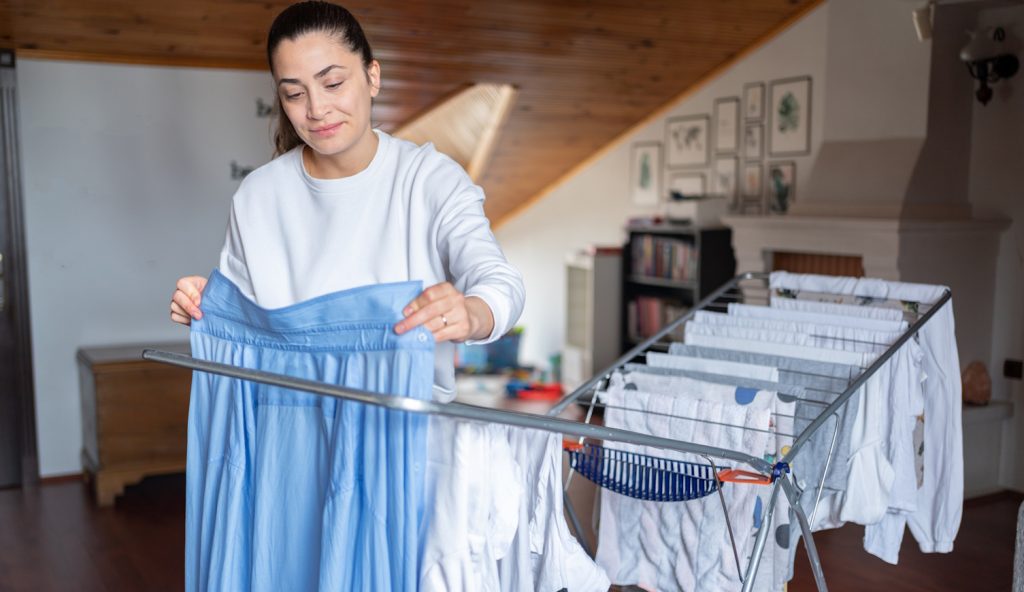 nő ruhákat tereget télen a lakásban