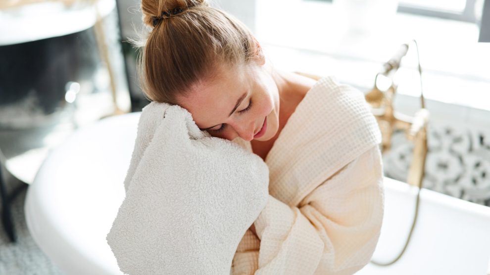 puha törölközővel arcot töröl egy fiatal nő