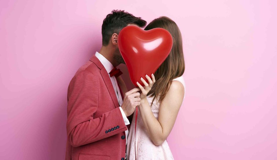 szerelmes pár egy szív alakú lufi mögött