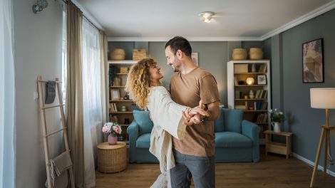 Boldog pár táncol a nappalijukban