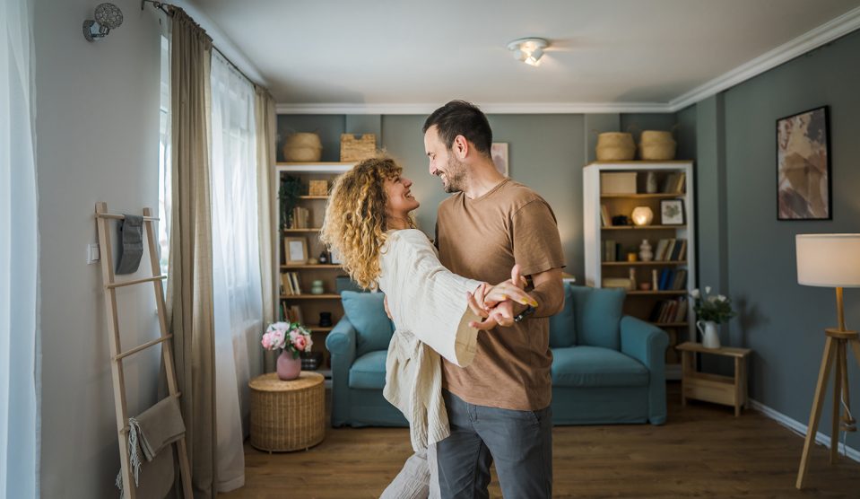Boldog pár táncol a nappalijukban