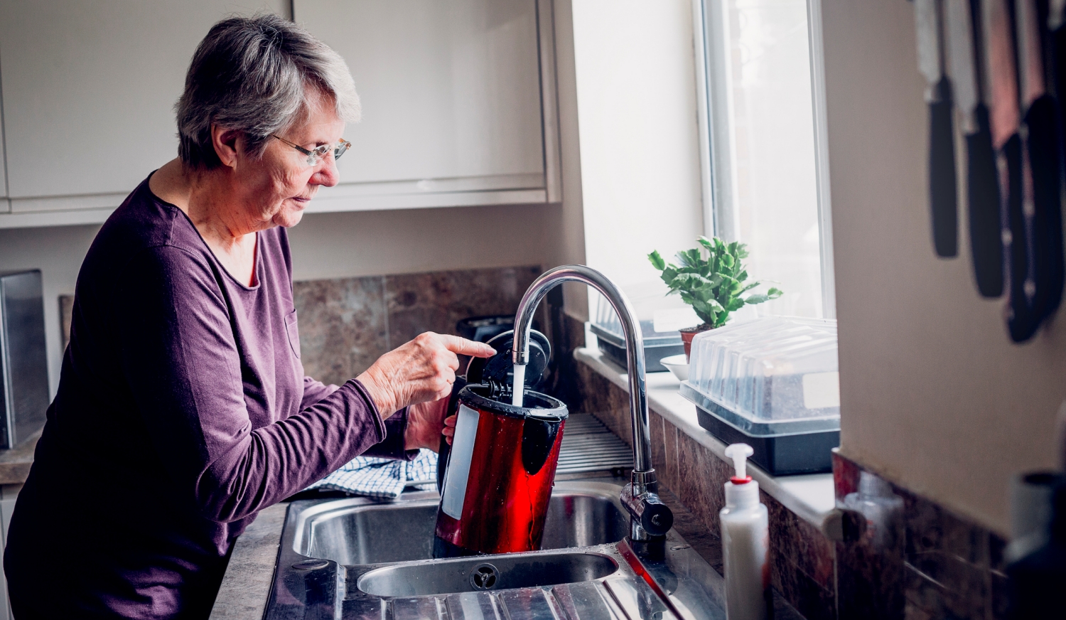 néni vizet tölt a vízforralóba