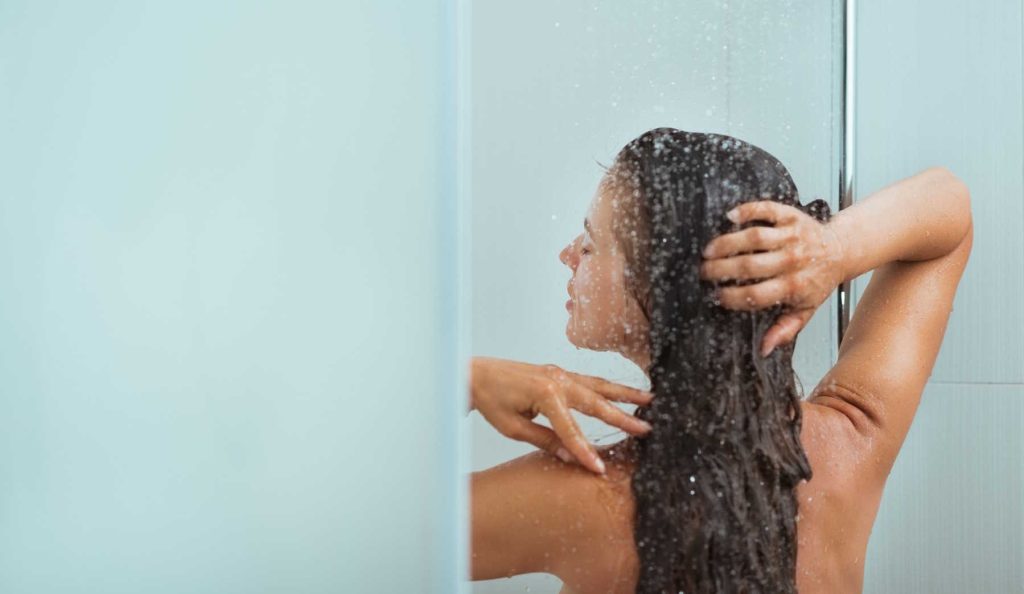 nő áll a zuhany alatt