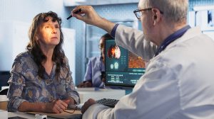 Egy orvos tollfénnyel vizsgál egy nőt az orvosi rendelőben