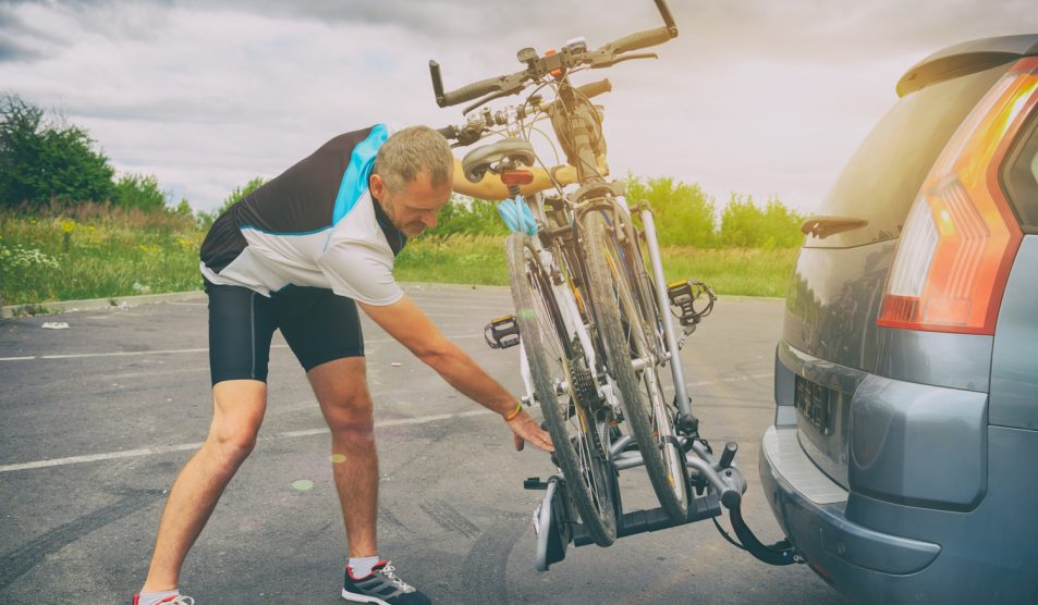 férfi biciklitárolót szerel fel az autó hátuljára