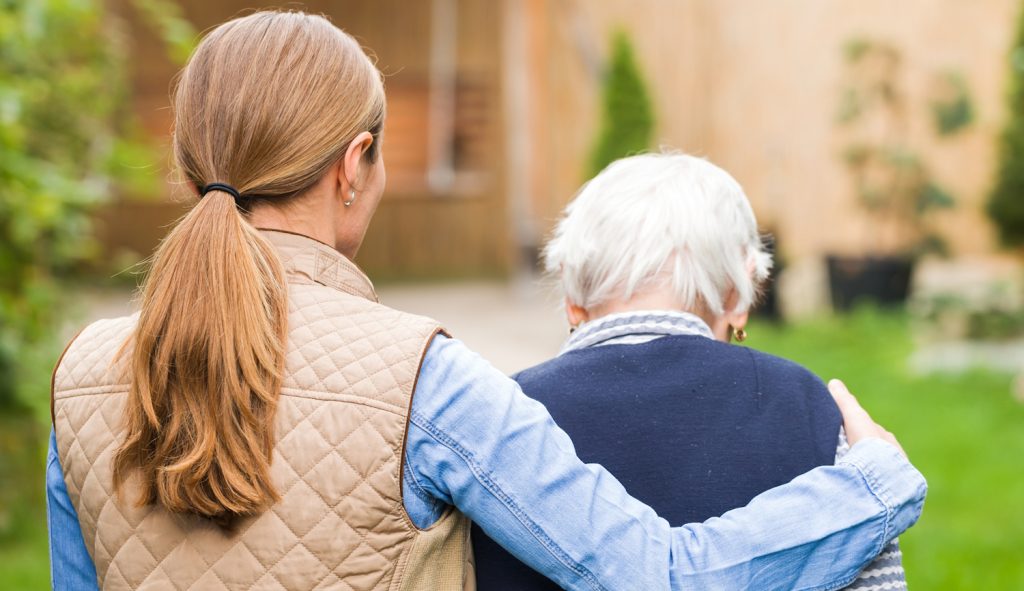betegápoló idős nőt kísér átkarolja