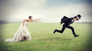 nő menyasszonyi ruhában fut a mezőn a vőlegény után