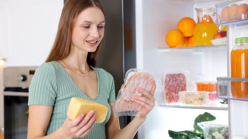 sajtot és felvágottat pakol a hűtőbe egy fiatal nő