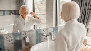 60 év feletti nő fogat mos a fürdőszobában