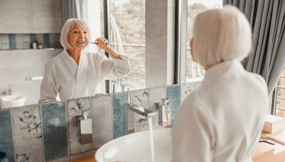 60 év feletti nő fogat mos a fürdőszobában