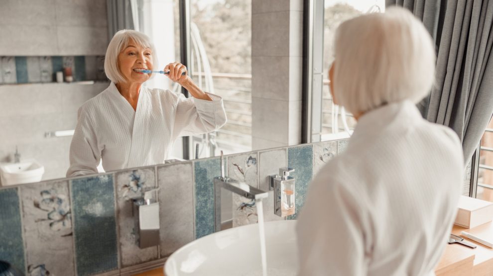 60 év feletti nő fogat mos a fürdőszobában