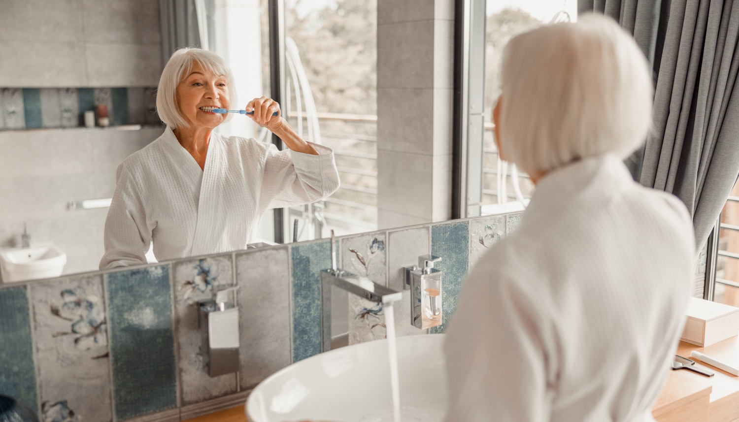 60 év feletti nő fogat mos a fürdőszobában