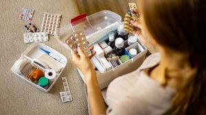 női kéz szépen elhelyezi a gyógyszert a háztartási elsősegélynyújtó készletben.