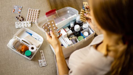 női kéz szépen elhelyezi a gyógyszert a háztartási elsősegélynyújtó készletben.