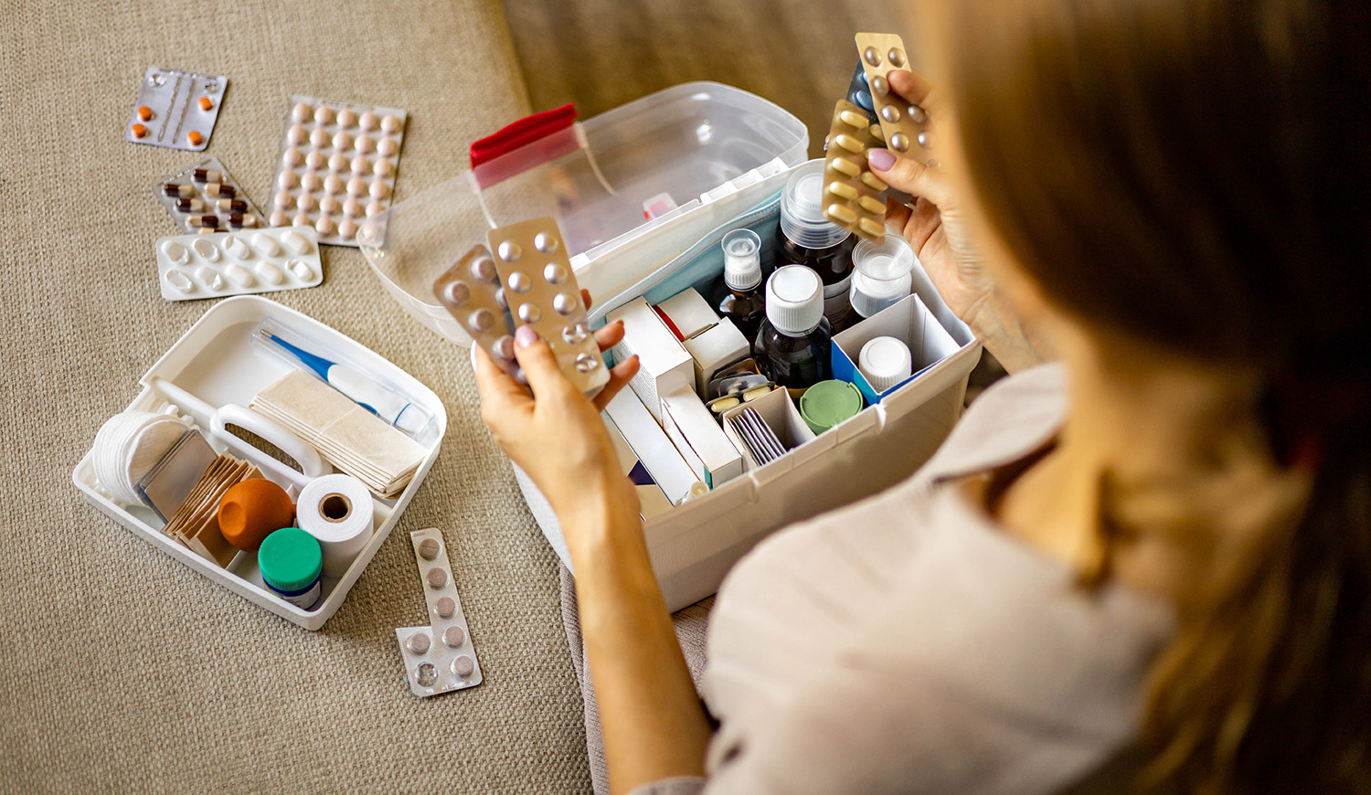 női kéz szépen elhelyezi a gyógyszert a háztartási elsősegélynyújtó készletben.