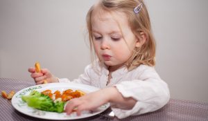 halrudacskát és sült krumplit eszik egy cuki kislány