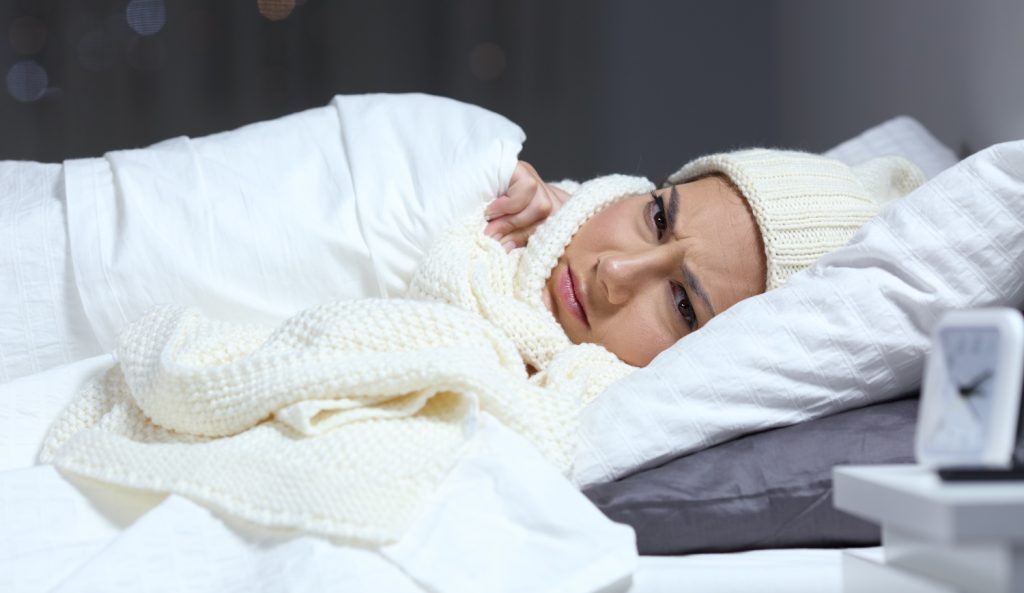 nő fázik az ágyban ezért sapkában sálban alaszik