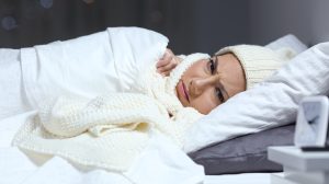 nő fázik az ágyban ezért sapkában sálban alaszik